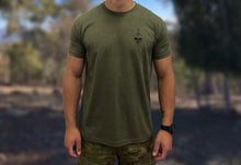 Australian soldier standing with camouflage plant and military green undershirt with a small chest piece of a skull and bayonet